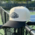 White and black cap with 'Pickleball' text on a tennis court